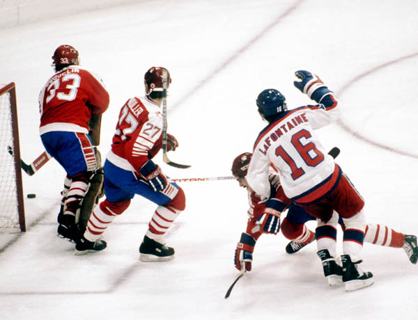 Mario Gosselin (gardien) et Kirk Muller (27) du Canada regardent la rondelle tandis que l'Amricain Pat Lafontaine trbuche lors d'un match de hockey aux Jeux olympiques d'hiver de Sarajevo de 1984. (Photo PC/AOC)