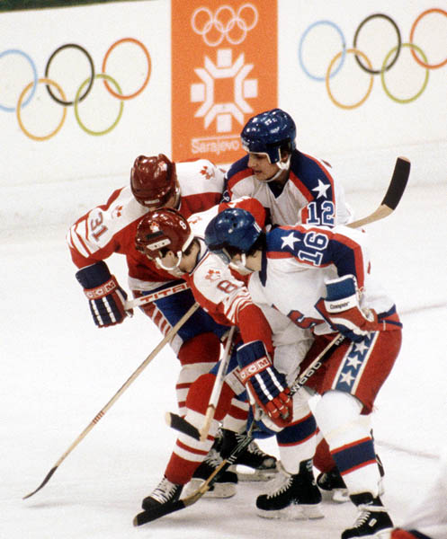 Canada' Vaughn Karpan (31) and Dave Tippett (8) scramble for the puck with United States players during hockey action  at the 1984 Winter Olympics in Sarajevo. (CP PHOTO/ COA/O. Bierwagon )