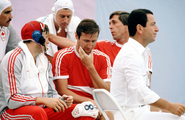Canada's coach for the men's waterpolo team Gabor Csepregi (centre) listens to a player at the 1984 Olympic Games Los Angeles. (CP Photo/COA/Tim O'lett)