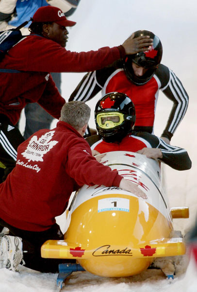 Canada's Pierre Leuders (front) and Giulio Zardo talk with their coaches (left) at the finish line of the two man bobsled at Utah Olympic Park during the Winter Olympics on Sunday Feb. 17, 2002. The pair finished the event in fifth place. (CP PHOTO/COA/Mi