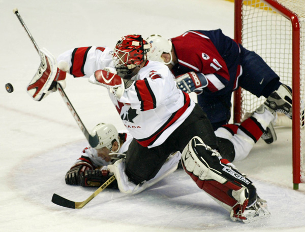Team Canada goalie Martin Brodeur makes a save as teammate Al Macinnis and Team USA John Leclair slide into the net during gold medal hockey action Sunday Feb. 24, 2002 at the 2002 Winter Olympic Games in Salt Lake City. Team Canada won 5-2 over Team USA.
