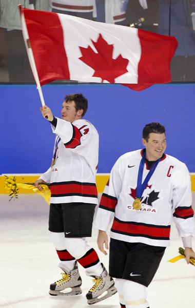 Team Canada captain Mario Lemieux smiles as Theo Fleury skates holding the Canadian flag after they won over Team USA to win the gold medal in hockey Sunday Feb. 24, 2002 at the 2002 Winter Olympic Games in Salt Lake City. Team Canada won 5-2 over Team US