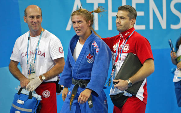 Marie Helene Chisholm (centre) of Varennes, Que. is consoled by her coach Ewan Beaton (right) of Montreal and medical staff member John Boulay of Beaconsfield, Que. after her loss to Urska Zolnir of Slovakia in 63kg judo action at the Athens Olympics, Tuesday, August 17, 2004.  (CP PHOTO/COC-Mike Ridewood)