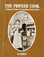 Cover of cookbook, THE PIONEER COOK: A HISTORICAL VIEW OF CANADIAN PRAIRIE FOOD, with an oval photograph of a pioneer woman standing beside a wood cooking stove and grinding coffee in a mill
