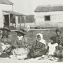 Photograph of a group of Aboriginal men, women and children seated on the ground at a feast, Mattagami, July 1906