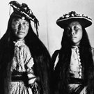 Portrait of Niviaqsarjuk (left) and Jennie (right) wearing Western style dresses and hats. This photograph was taken in a studio at Fullerton, Nunavut, 1904