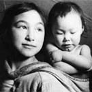 Photograph of an Inuit girl carrying an infant in a baby-pouch, Taloyoak (formerly Spence Bay), Nunavut, circa 1961