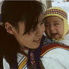 Photo couleur d'une jeune mère inuite portant son enfant dans un porte-bébé, Igloolik (Iglulik), Nunavut, mai 1965