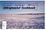 Cover of cookbook, QIKIQTAMIUT COOKBOOK, featuring a photograph of a northern community on a snow-covered tundra