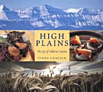 Cover of cookbook, HIGH PLAINS: THE JOY OF ALBERTA CUISINE, with a photograph of the Rockies, with another photograoh below it of a field of wheat, with photos of fish dishes on either side of the title