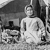 Photo d'une jeune Autochtone assise au sol prise durant les paiements du Traité nº 9 dans la région de la baie James (Ontario), 1906.
